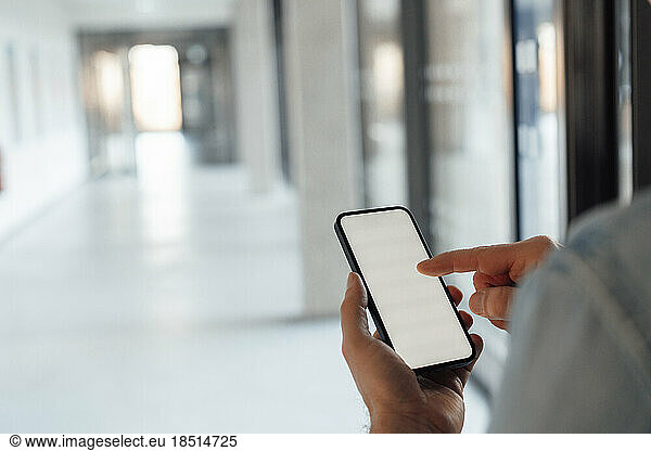 Businessman touching screen of smart phone at corridor