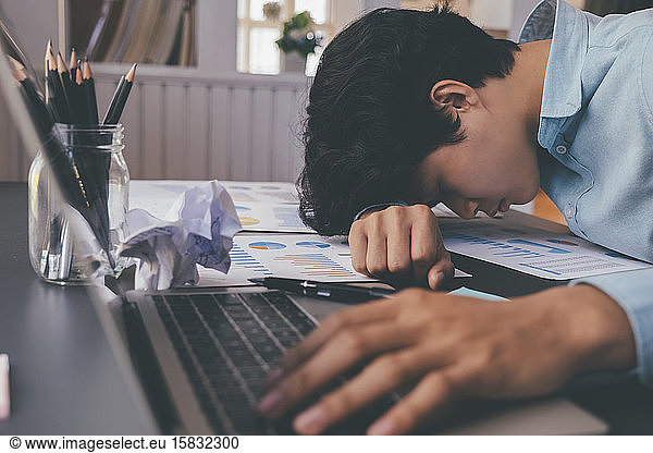 Businessman tried and stressed sleep on working desk.