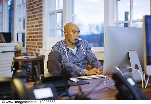 Businessman using desktop computer while sitting at desk in office