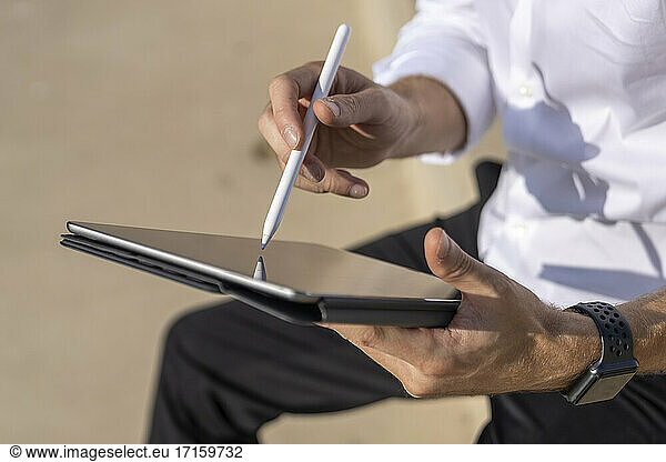 Businessman using digital table while sitting outdoors on sunny day