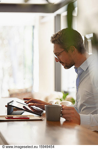 Businessman using digital tablet and drinking coffee  working from home
