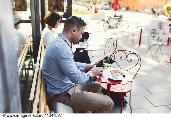 businessman using digital tablet at sidewalk cafe