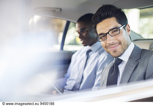Businessman using digital tablet in car back seat