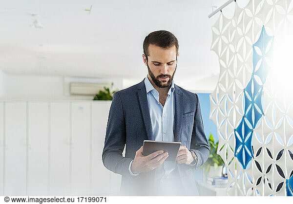 Businessman using digital tablet while standing at office