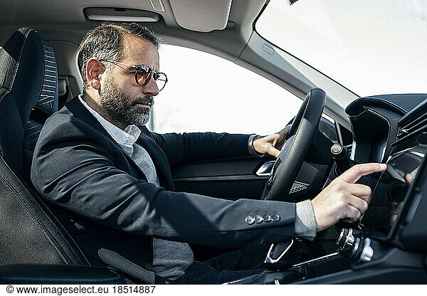 Businessman using GPS system sitting in electric car
