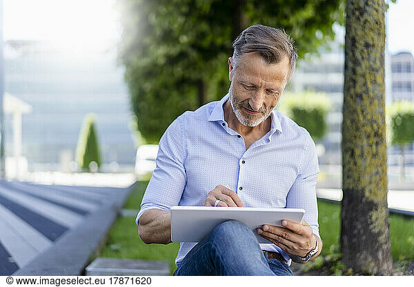 Businessman using graphic tablet sitting at office park