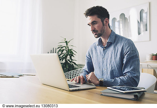 Businessman using laptop computer at desk in office