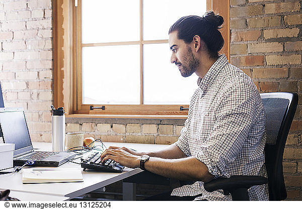 Businessman using laptop computer while sitting at desk in office