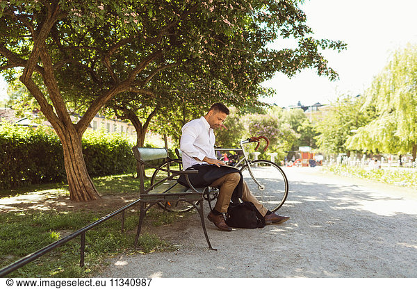 Businessman using laptop while sitting on bench at park
