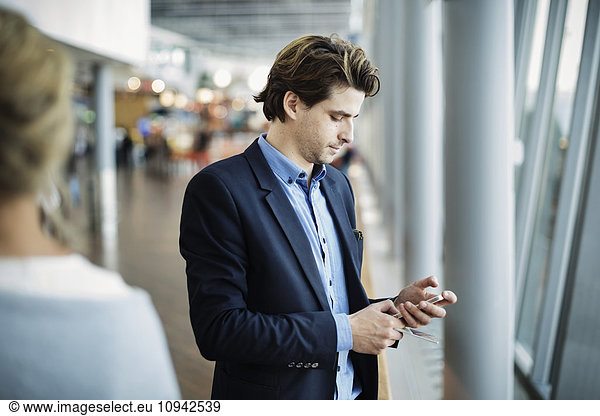 Businessman using mobile phone at airport