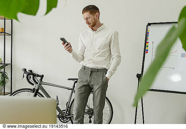Businessman using mobile phone in front of wall