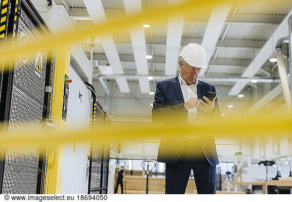 Businessman using mobile phone standing in industry