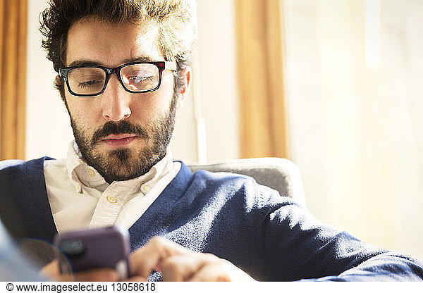 Businessman using phone while sitting at home