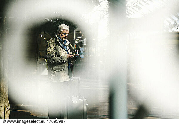 Businessman using smart phone while standing at railroad station