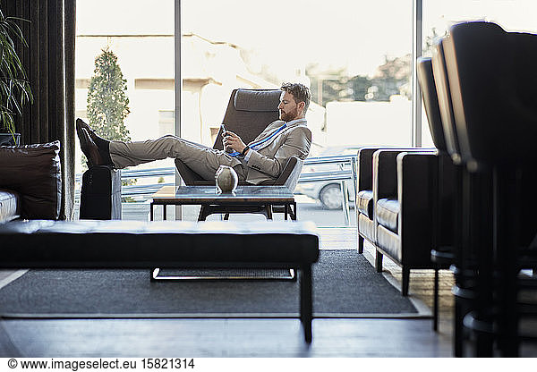 Businessman using smartphone in hotel lobby