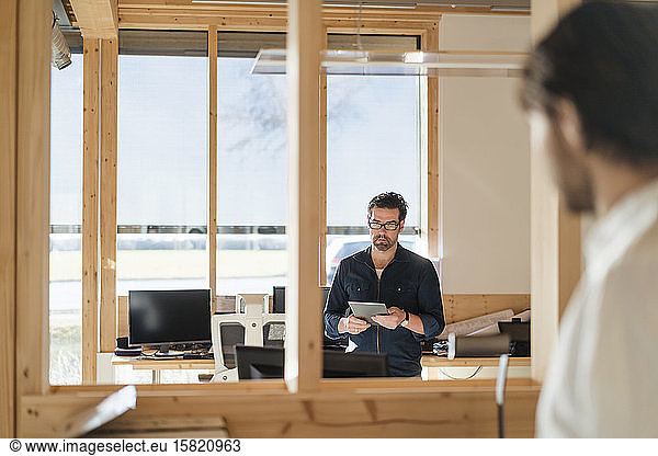 Businessman using tablet in wooden open-plan office