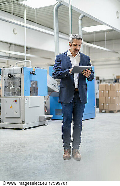 Businessman using tablet PC in factory