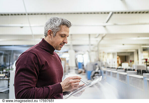 Businessman using tablet PC working in factory
