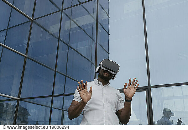 Businessman using virtual reality simulator in front of glass building