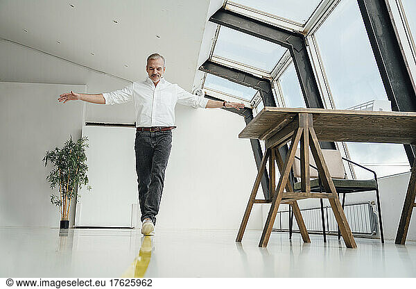 Businessman walking over yellow striped marking on floor in office