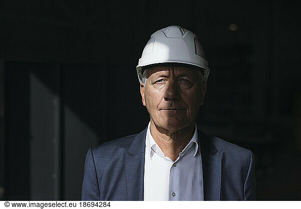 Businessman wearing blazer and hard hat in factory
