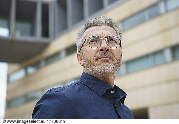 Businessman wearing eyeglasses in front of office building
