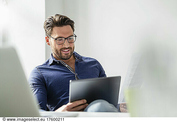 Businessman wearing eyeglasses using tablet PC at office