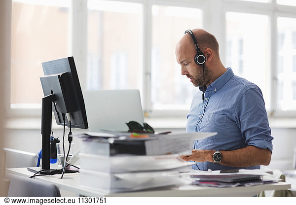 Businessman wearing headphones working at desk in office