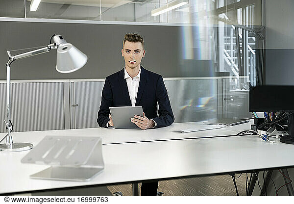 Businessman wearing suit using digital tablet while sitting at office