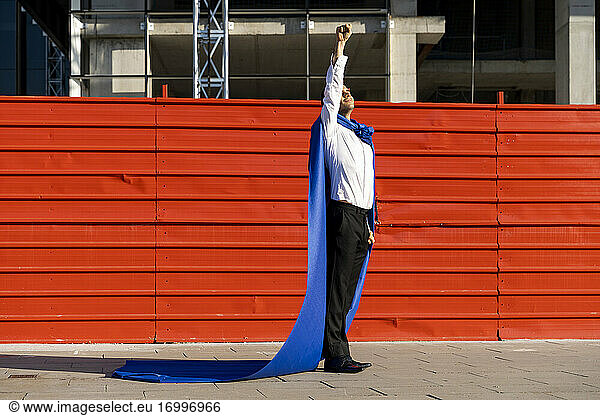 Businessman wearing superhero cape clenching fist