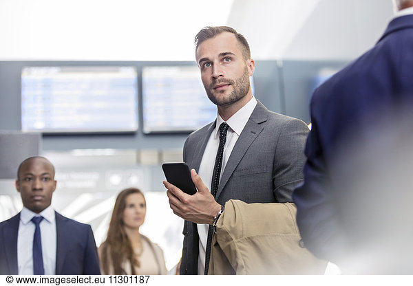Businessman with cell phone standing in airport