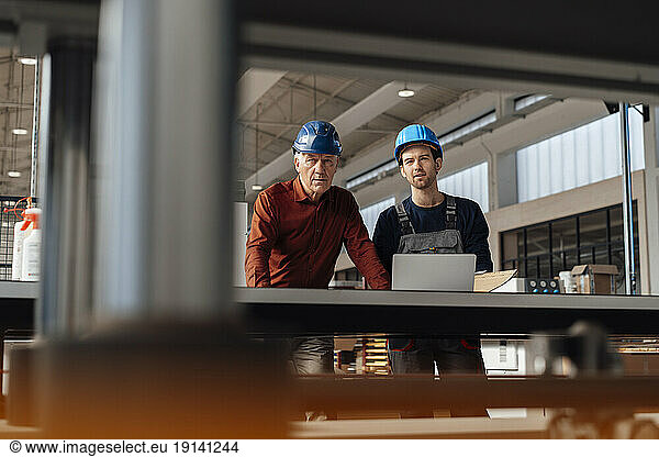 Businessman with colleague examining machinery at factory