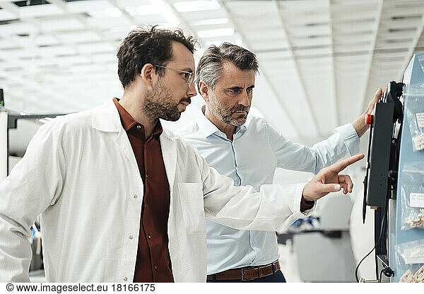 Businessman with colleague operating machine at industry