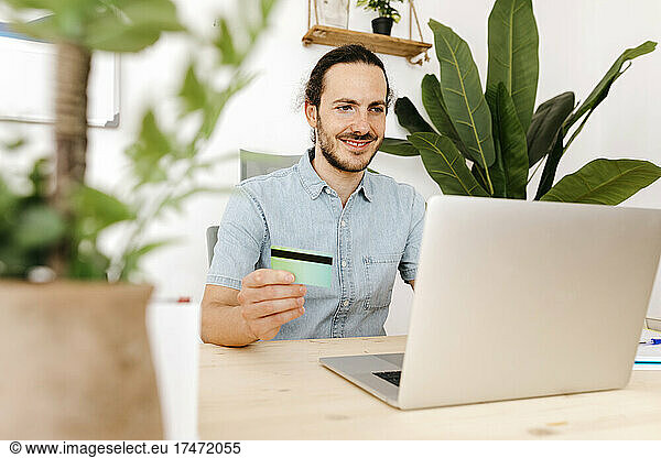 Businessman with credit card and laptop at office