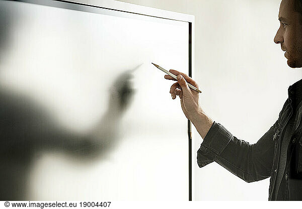 Businessman with digitized pen writing on interactive whiteboard