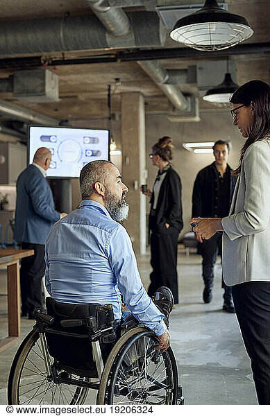 Businessman with disability talking to businesswoman at creative office
