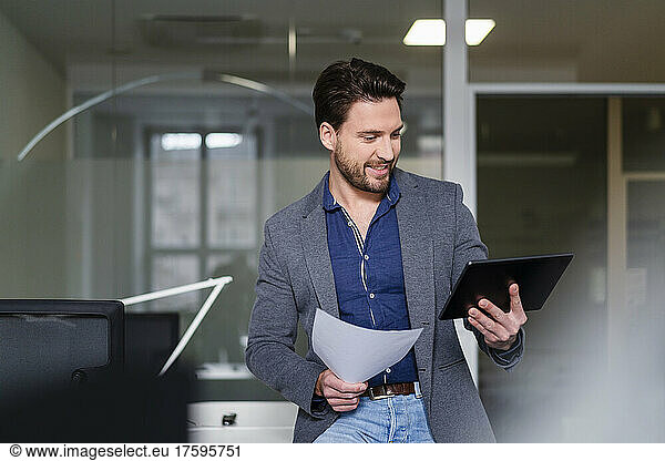 Businessman with document using tablet PC in office