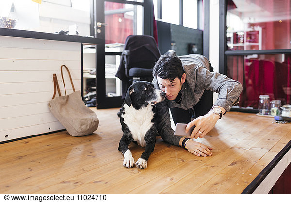 Businessman with dog taking selfie through smart phone at office