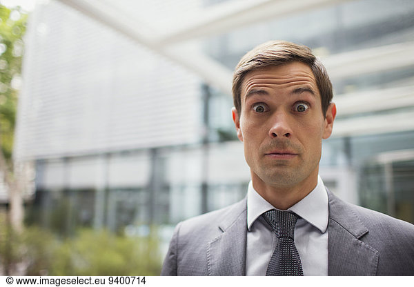 Businessman with eyebrows raised outside office building