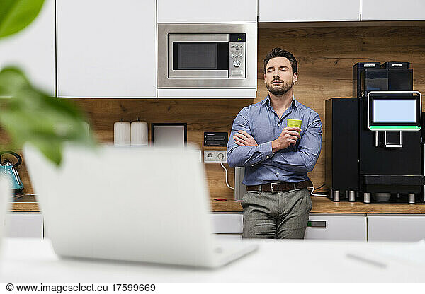 Businessman with eyes closed standing at home office