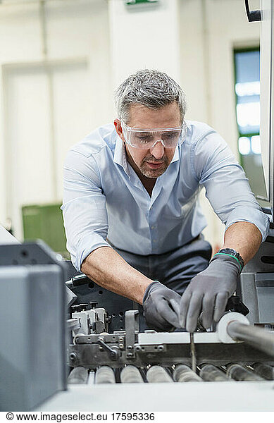 Businessman with gray hair examining machinery in factory
