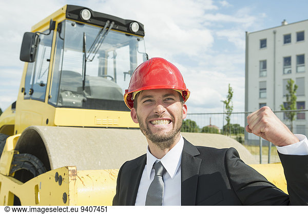 Businessman with hard hat cheering on construction site