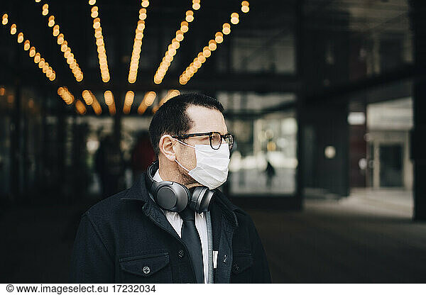Businessman with headphones looking away during pandemic
