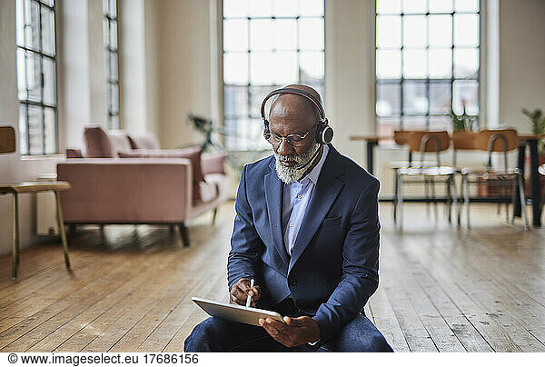 Businessman with headset using tablet PC with digitized pen at home
