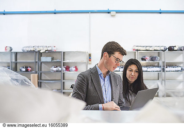 Businessman with laptop and female employee in a warehouse