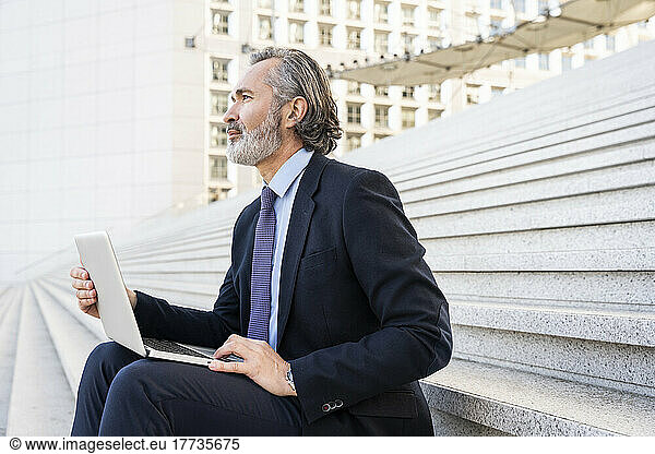 Businessman with laptop sitting on staircase