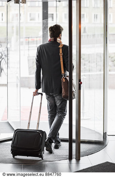 Businessman with luggage leaving hotel