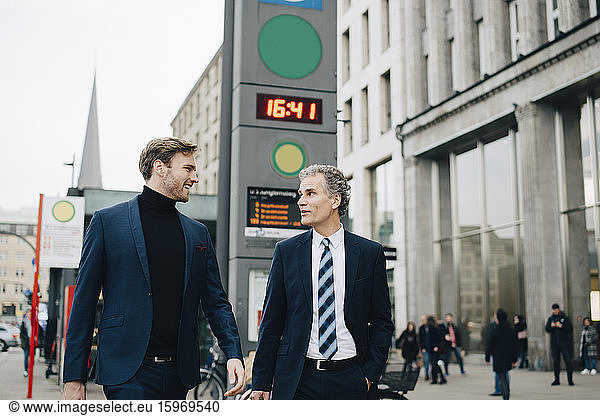 Businessman with male colleague walking in city