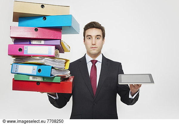 Businessman with stacks of folders and tablet computer