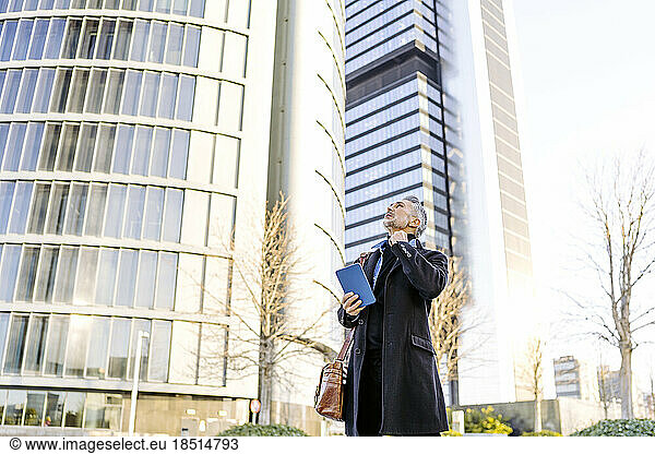 Businessman with tablet PC standing in front of buildings